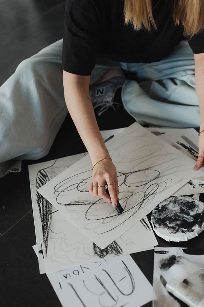 Kunstlerin beim Skizzieren auf Papier mit Bleistift und Kreide, kreative Arbeit im Atelier.