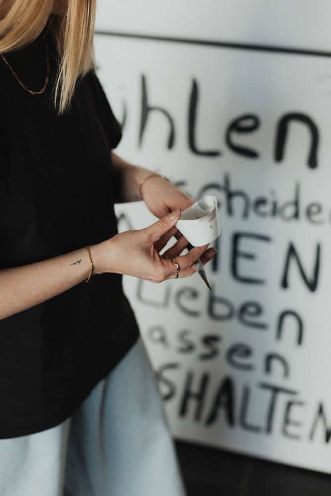 Frau hält Marker vor Whiteboard mit deutschen Texten, Fokus auf Hand und Marker.