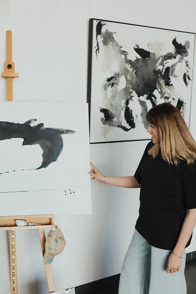 Frau betrachtet abstrakte Tierkunstwerke in Schwarz-Weiß an einer weißen Wand.