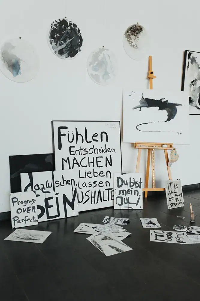 Kunstinstallation mit Schriften, Gemälden und Drucksachen in einem kreativen Raum.