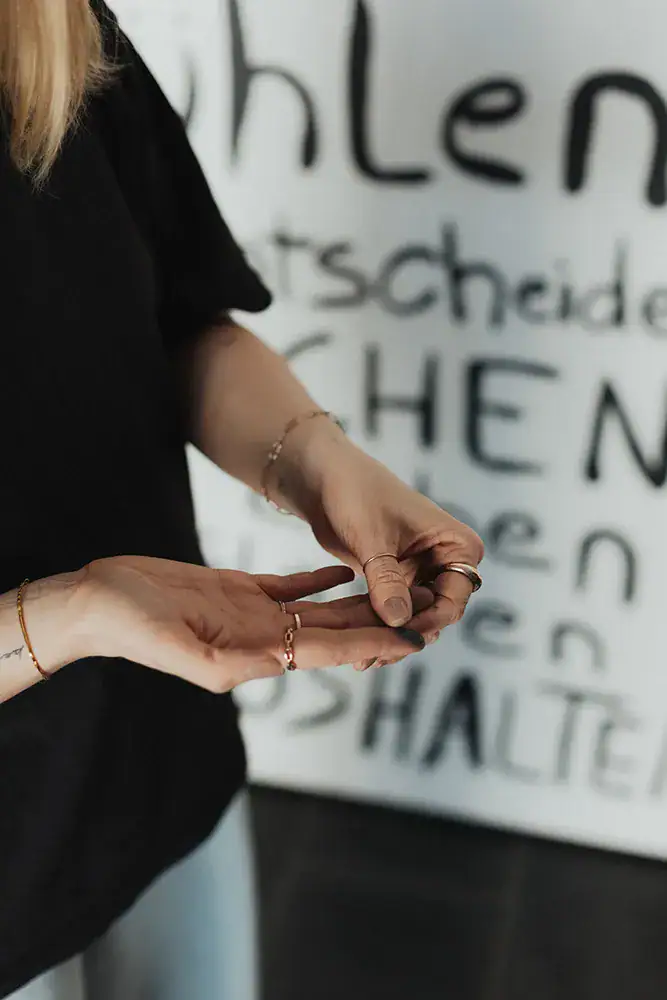 Hände in Meditationshaltung vor einem weißen Hintergrund mit Text.