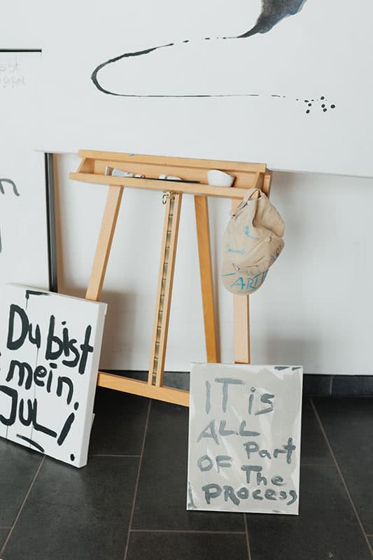 Drei Leinwände mit handgeschriebenen Texten vor einer Staffelei