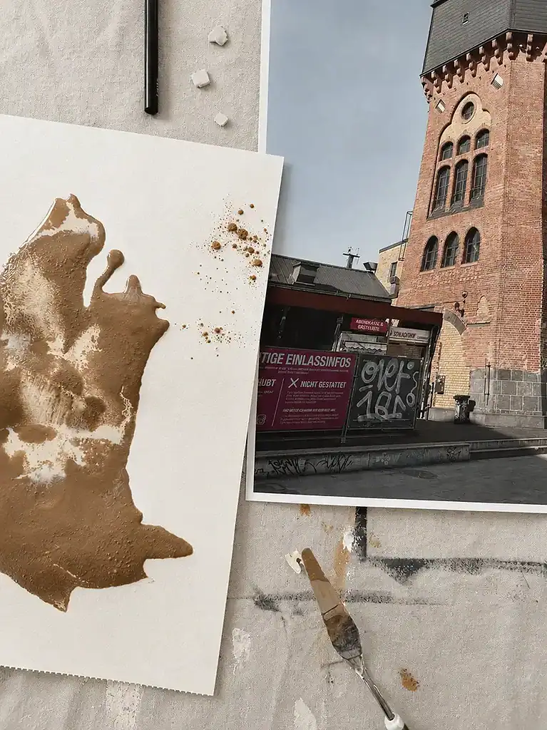Kreatives Mal-Setup mit Foto, abstrakt bemaltes Papier und Pinsel auf einem Tisch