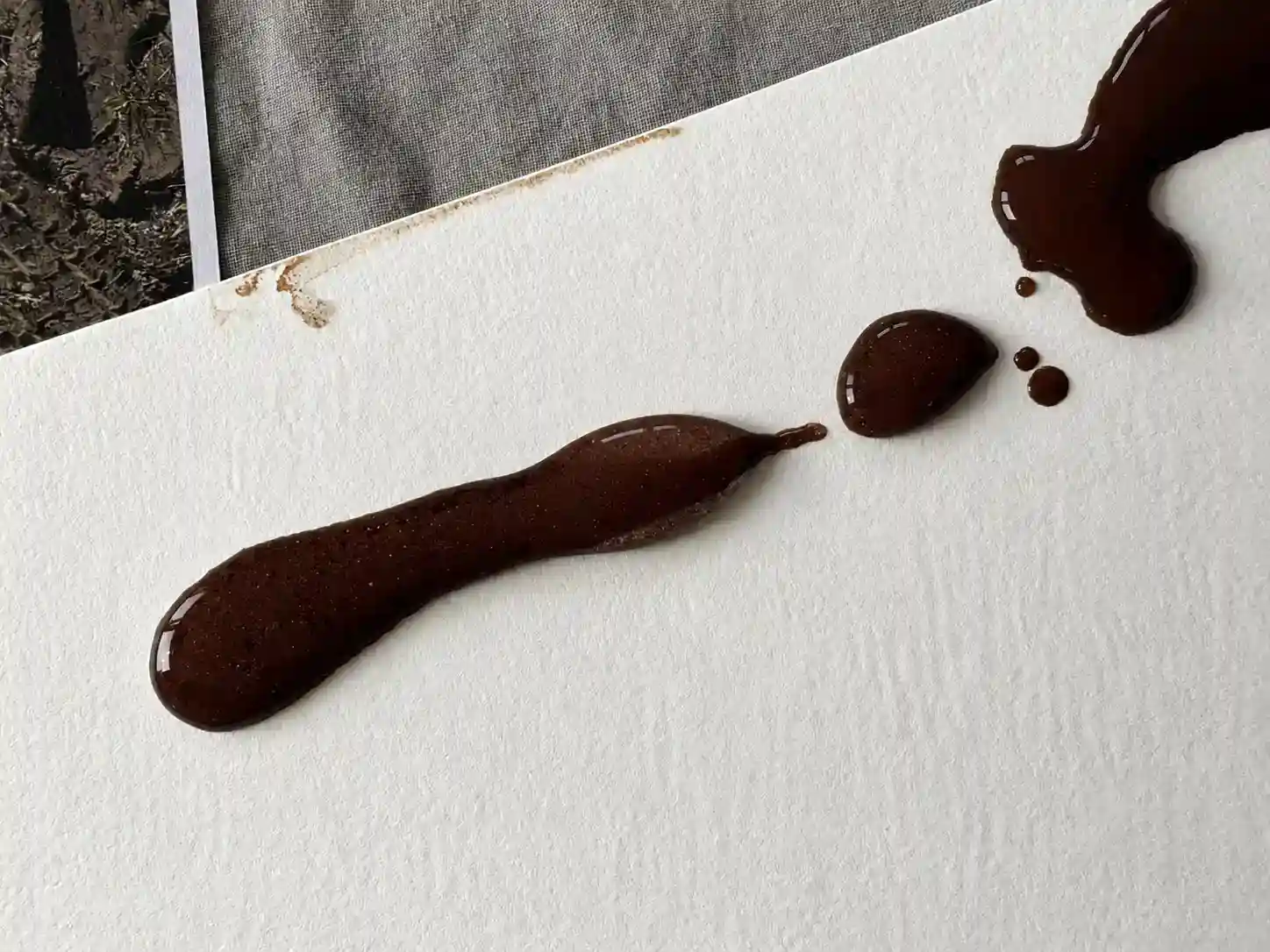 Nahaufnahme von flüssigen dunklen Farbspritzer auf weißem Papier