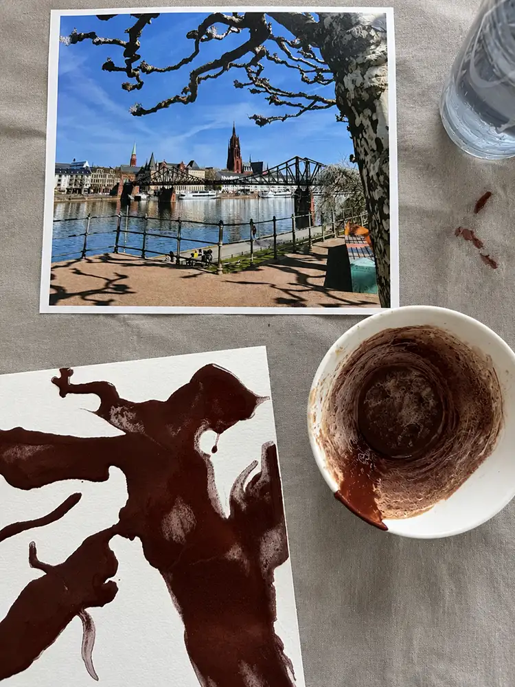 Kreatives Mal-Setup mit Foto mit Stadtpanorama, bemaltes Papier, Pinsel und Farben auf einem Tisch