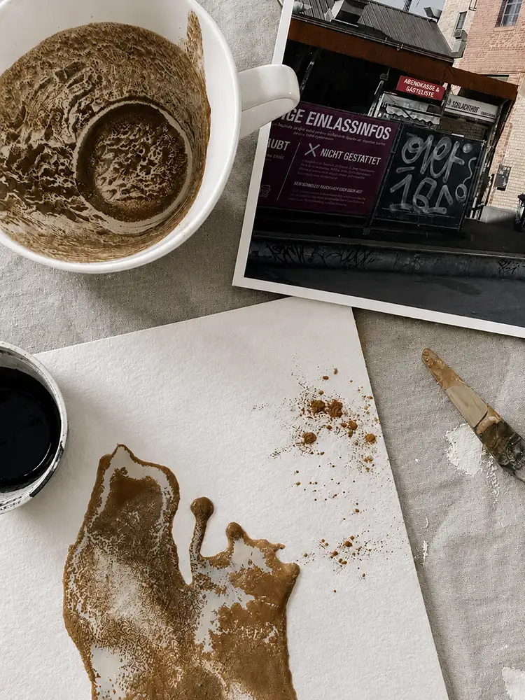 Kreatives Mal-Setup mit Foto, bemaltes Papier, Pinsel und Farben auf einem Tisch