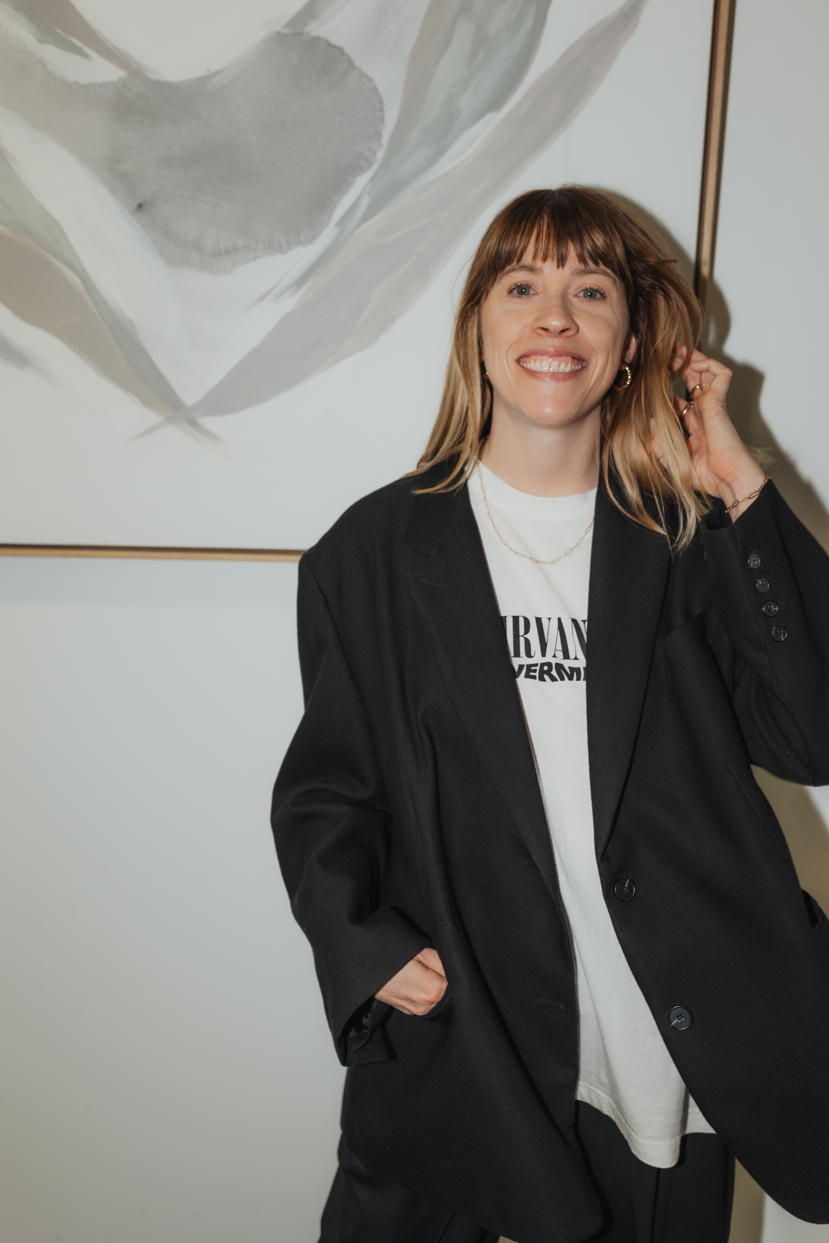 Frau in Kunststudio mit abstrakten Wandbildern und Malutensilien, kreative Atmosphäre.